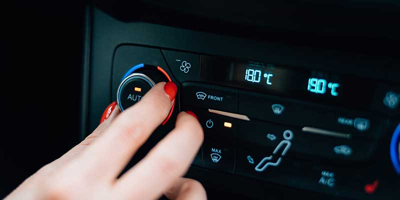 a person's hand changing the a/c temperature in a vehicle
